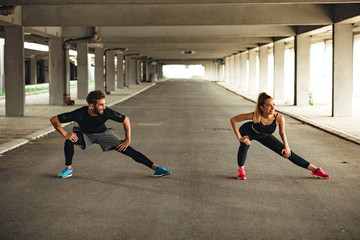 Fototapeta premium Young couple stretching before workout outdoor