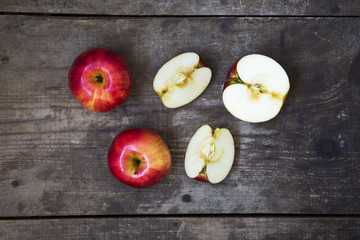 Ripe red apples and slices on dark wooden background. From above. Top view