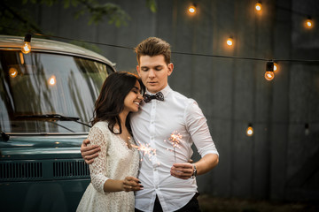 Merry happy young couple hugging near a retro minivan. Close-up.