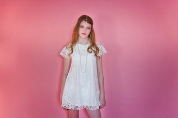 Happy teenage girl smiling. Closeup portrait young happy positive woman wearing white dress standing on pink colourful pastel trendy modern fashion pin-up background. European woman. Positive human em