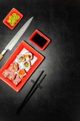 Set of sushi, Japanese knife, chopsticks and on dark stone table. Top view with copy space. Wasabi, soy sauce. Sushi on a table.