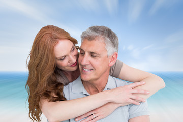 Casual couple hugging and smiling against beach scene