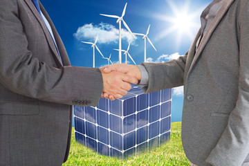 Close up on two businesspeople shaking hands against turbines on a cube made of solar panels