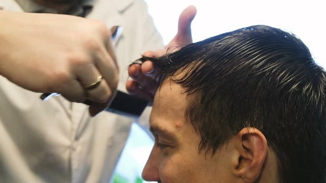 Hairdresser cuts a man with a razor in barbershop