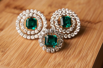 Emerald ring and pair of diamond earrings in gold, wedding jewelry with luxury gift box , close-up. Selective focus