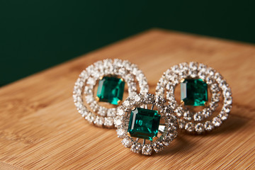 Emerald ring and pair of diamond earrings in gold, wedding jewelry with luxury gift box , close-up. Selective focus