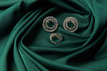 Emerald ring and pair of diamond earrings in gold, wedding jewelry with luxury gift box , close-up....