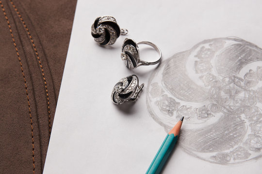 Beautiful diamond earrings and a ring with a picture on white paper. Luxury jewelry, close-up. Selective focus