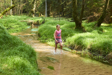 Obraz premium Child cute blond girl playing in the creek. Summer children fun. 