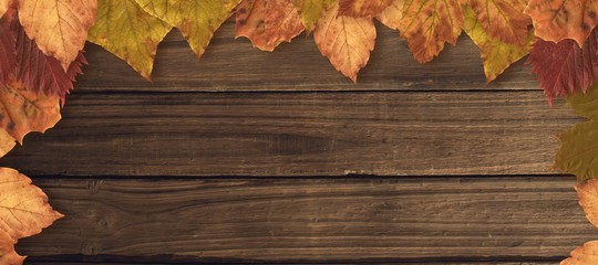 Fototapeta na wymiar Autumn leaves pattern against overhead of wooden planks