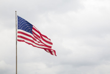 American Flag with a Blue Cloudy Sky - Powered by Adobe