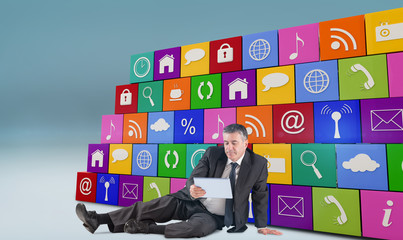 Mature businessman sitting using tablet against blue vignette background