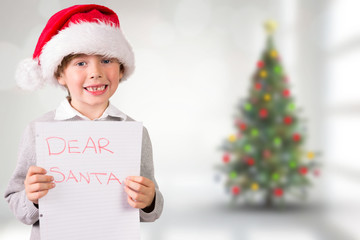 Festive boy showing letter against blurry christmas tree in room