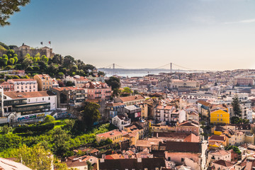 Fototapeta na wymiar Panoramic image of the city of Lisbon, Portugal. Some buildings in the center of the city, the castle of San Jorge and the famous bridge of April 25 in the background above the Tejo river.