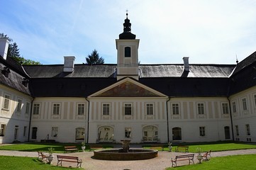 Inner courtyard of baroque mansion in Svaty Anton, central Slovakia, during late spring season, chapel tower and fountain visible.