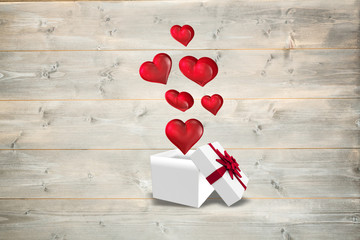 Hearts flying from box against bleached wooden planks background