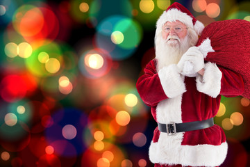 Santa carries his red bag and smiles against colourful glowing dots on black