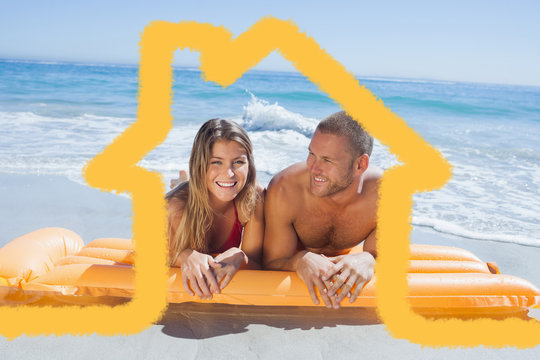 Cheerful cute couple in swimsuit lying on the beach against house outline