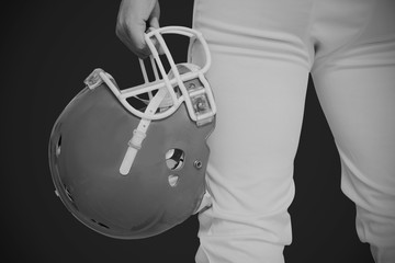 American football player holding a helmet against black