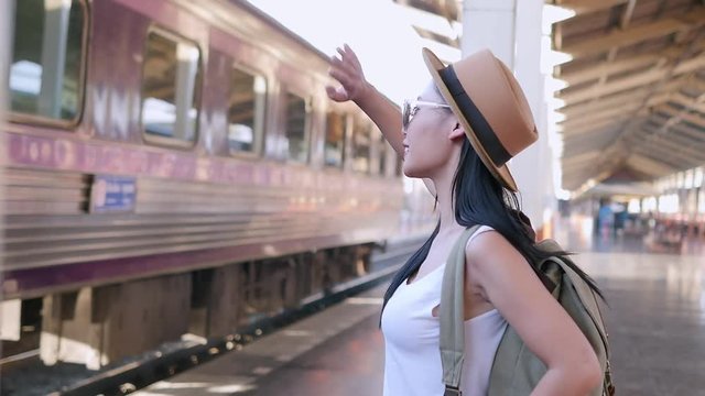 Woman traveler wave her hand to people in moving train - young traveler at train station concept