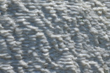 Wet wavy travertine calc tuff mound texture. White colour is mostly calcium carbonate sedimented from mineral water