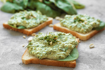 Toasts with tasty spinach sauce on table