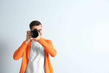 Male photographer with camera on light background