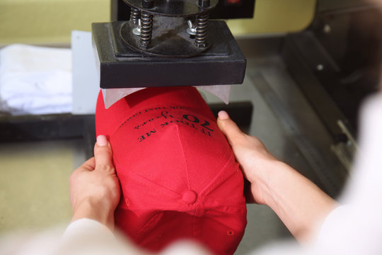 Young woman printing on cap at workshop