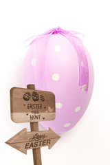 Easter egg hunt sign against purple hand painted easter egg