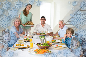 Family having meal at dining table against snowflake frame