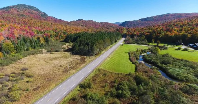 Drone over road with surrounding mountains and fall foliage 