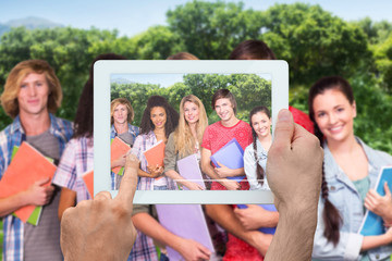 Hand holding tablet pc against park on sunny day