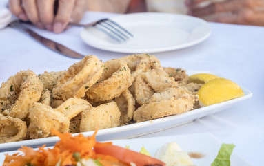 Fried Calamari Served with Wedges of Lemon in a Restaurant