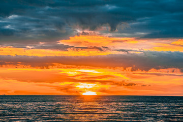 Fototapeta na wymiar Burning orange sun almost under the horizon - beautiful minimalist seascape