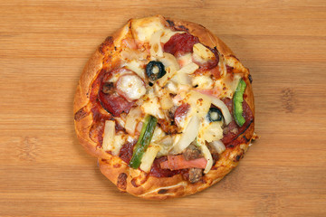 Pizza beef chicken peperoni cheese chilli capsicum onion olive on wooden board