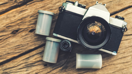 Old camera and film cassette on wooden board view from the top, retro color effect, select focus