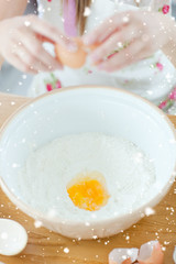 Delighted woman preparing a cake in the kitchen with snow falling