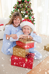 Obraz na płótnie Canvas Composite image of Happy brother and sister holding Christmas presents with snow falling