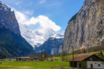 Sunny summer view of amazing touristic alpine village with famous church and Staubbach waterfall, Lauterbrunnen, Switzerland, Europe