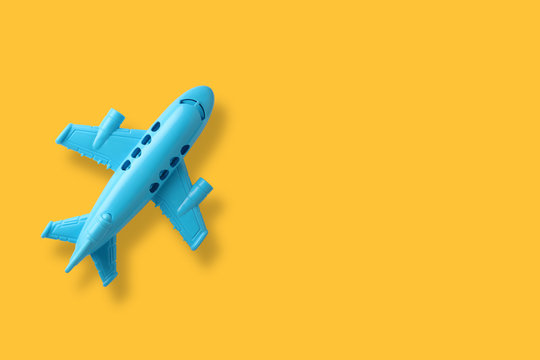 blue plastic toy plane on yellow background with space
