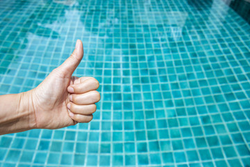 Girl hand over clear blue swimming pool water, great pool, like hand, hand thumb up sign, outdoor day light