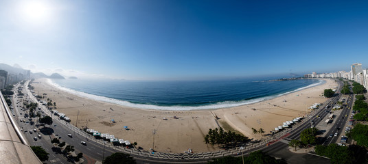 full panorama view of Copacabana beach during early morning, taken from the rooftop of a hotel, some slight fog can be seen on the blue sky. Rio de Janeiro, Brazil