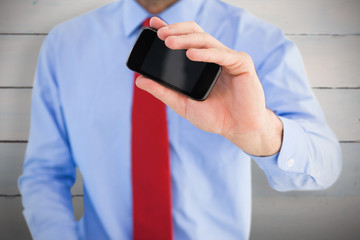 Hand of businessman showing smartphone against painted blue wooden planks