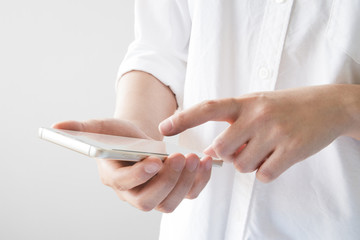 Obraz premium Woman with mobile phone in hands touching on the screen in white room, isolate on white background
