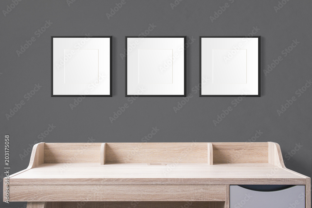 Aufkleber working table with blank photo frames in the empty studio with black wall.