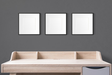 working table with blank photo frames in the empty studio with black wall.