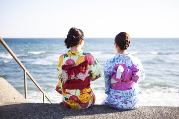浴衣を着た女性たちは海辺に座っている