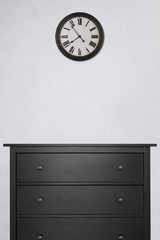 black wooden cabinet and clock in empty room with white cement wall. vintage style, black and white