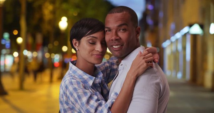 Happy young ethnic boyfriend and girlfriend on vacation in France posing intimately for the camera, African-American couple standing together romantically on the Champs-Elysees, 4k
