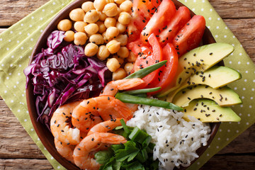 Healthy Buddha bowl with raw vegetables, shrimp, chickpeas, rice and greens close-up. horizontal top view